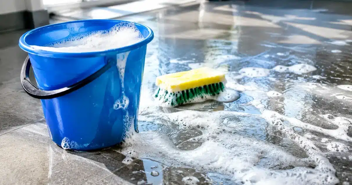 Seau d'eau savonneuse avec sol brillant recouvert de mousse blanche