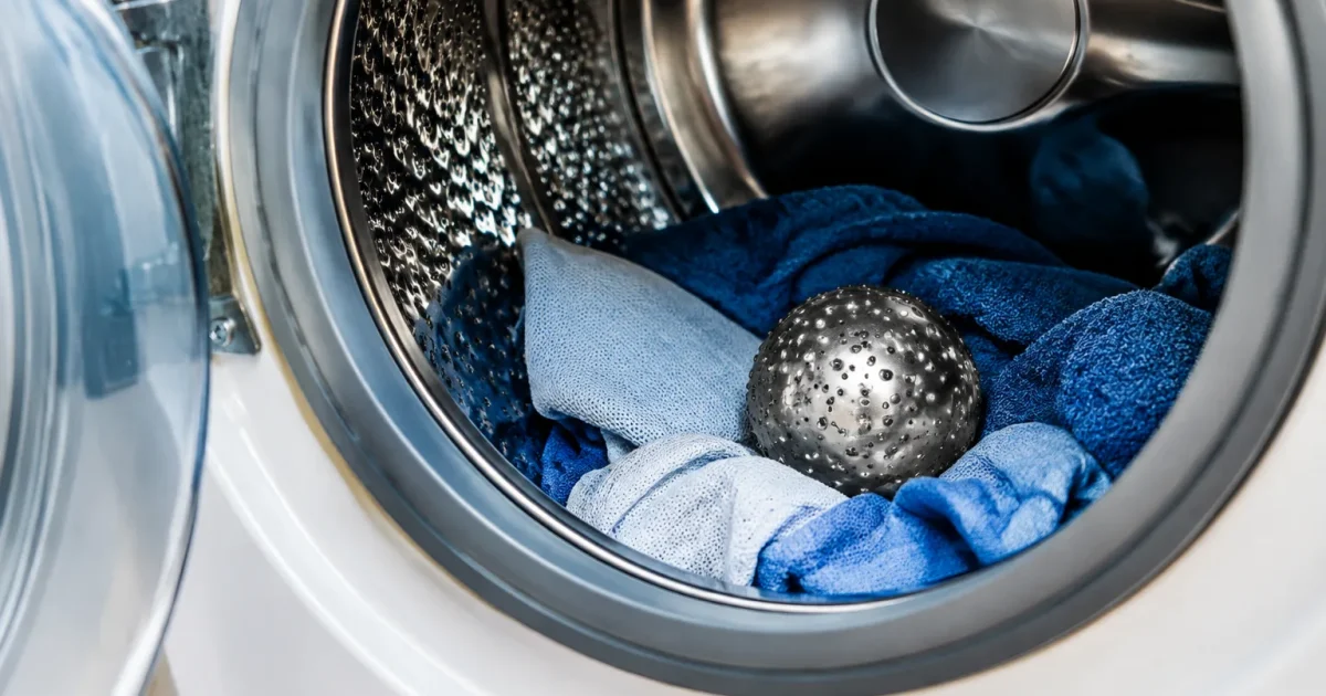 Boule metallique argentee posee dans tambour machine a laver ouvert