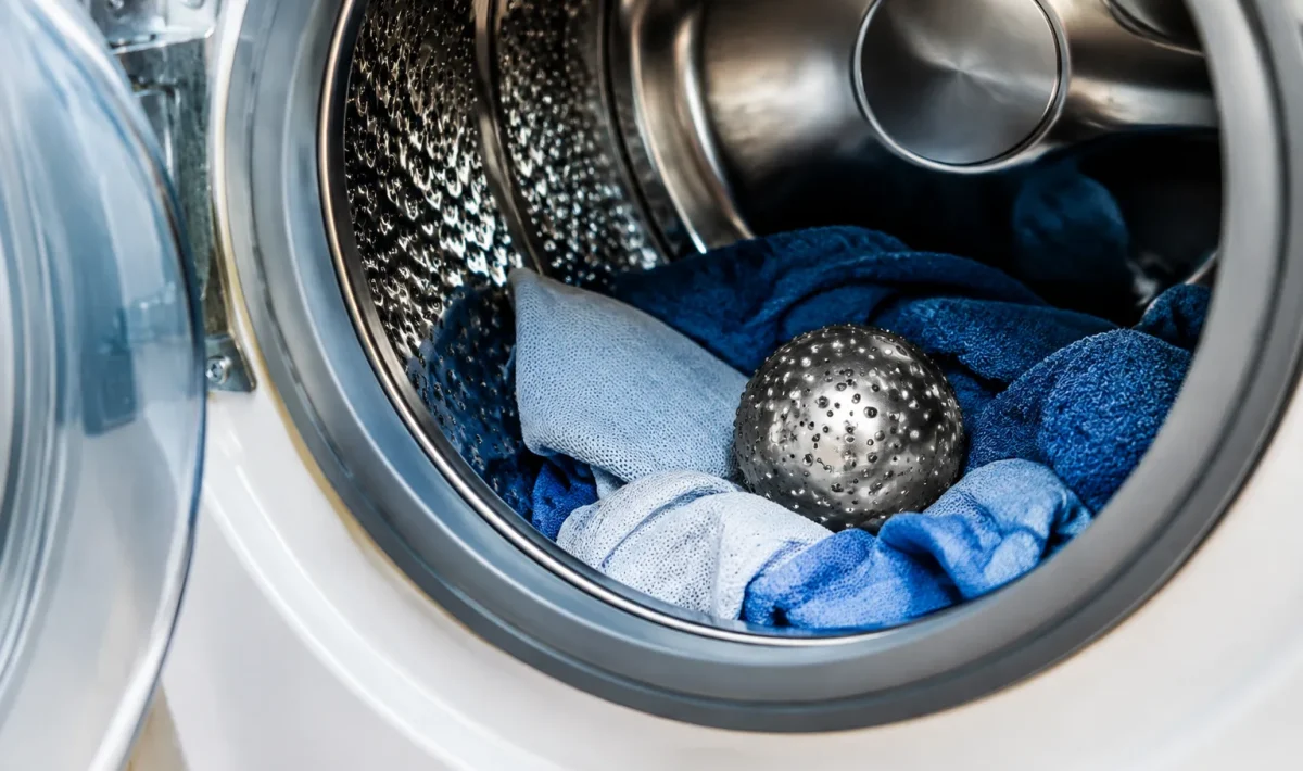 Boule metallique argentee posee dans tambour machine a laver ouvert