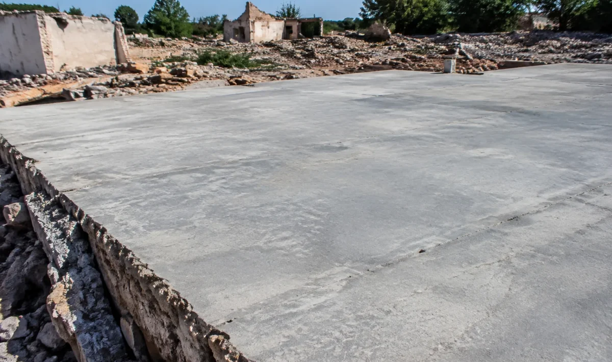 Vaste dalle beton grise recouvrant completement les decombres d'habitations anciennes