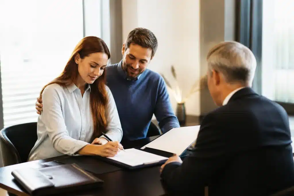 Parents signant documents immobiliers devant notaire assis