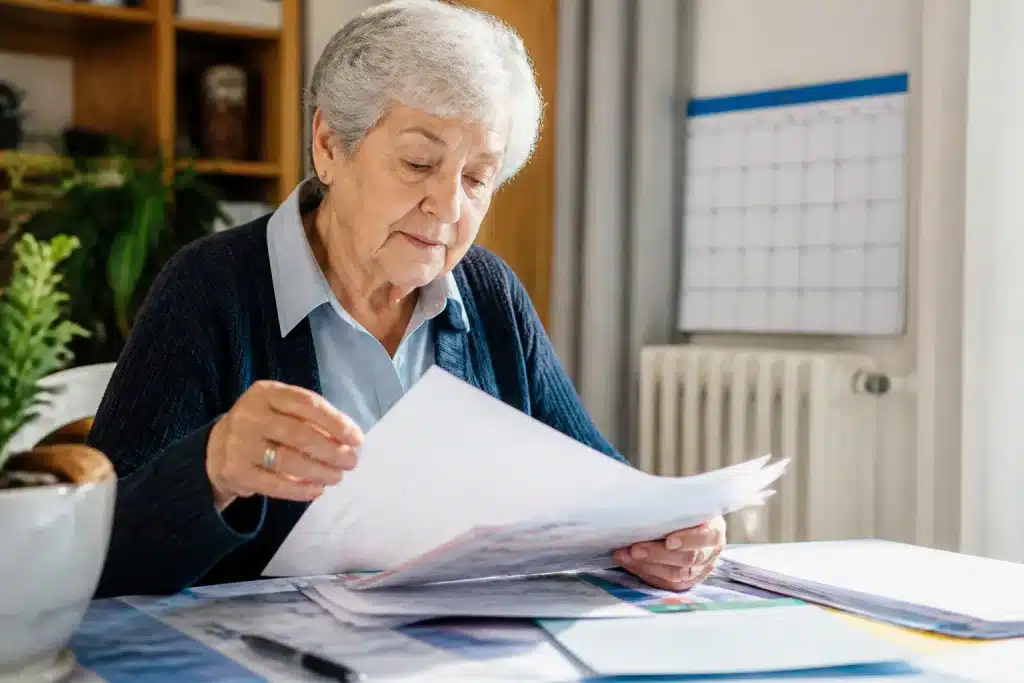 Personne agee feuilletant documents administratifs avec calendrier visible