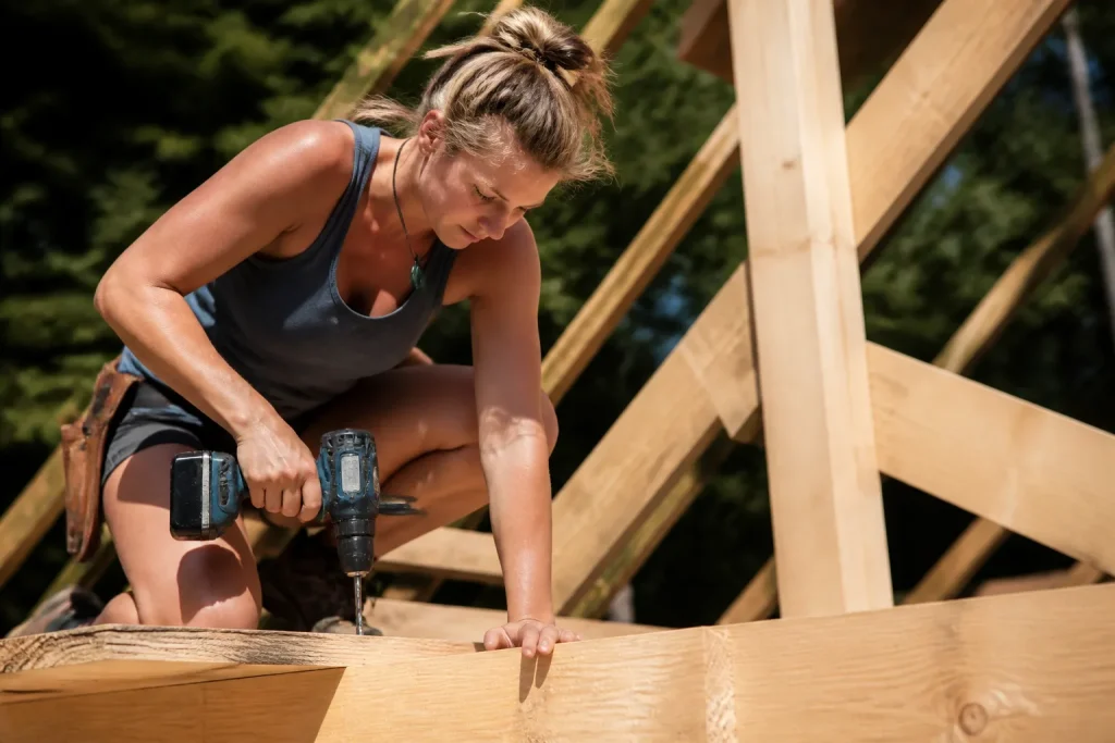 Femme percant du bois pour cadre charpente
