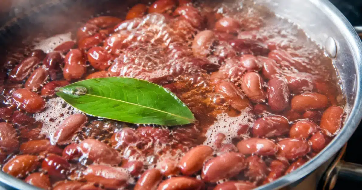 Feuille verte flottant à la surface d'une casserole de haricots bouillants