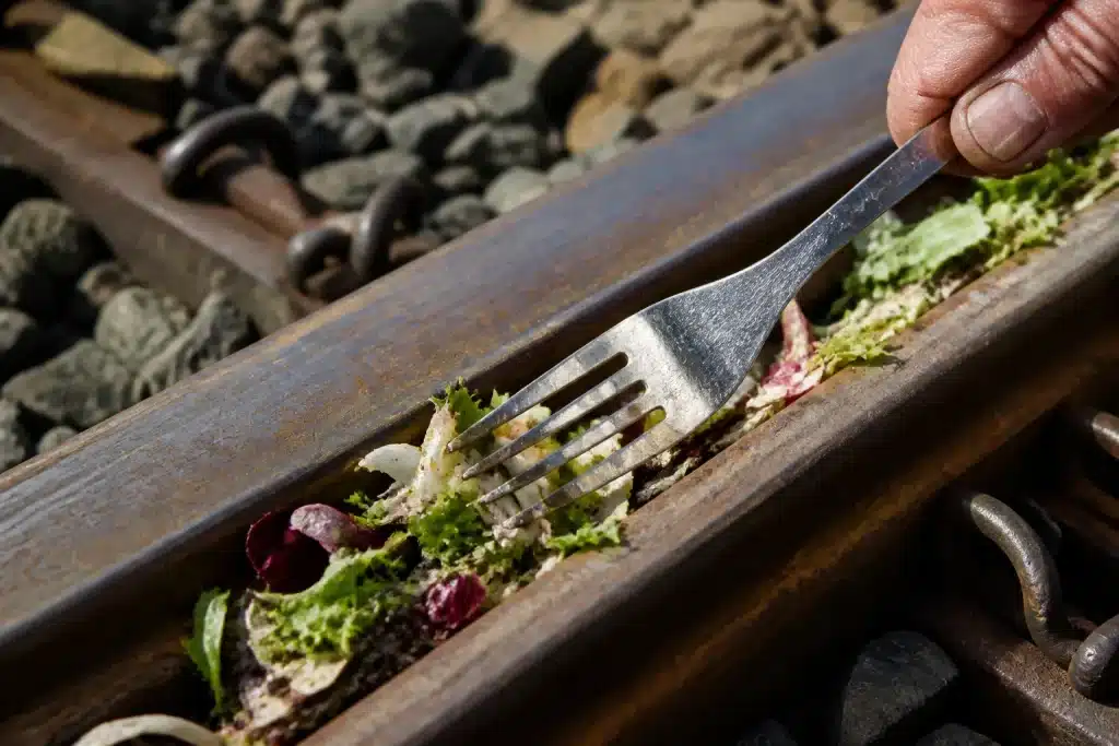 Fourchette nettoyant une salade incrustée dans un rail