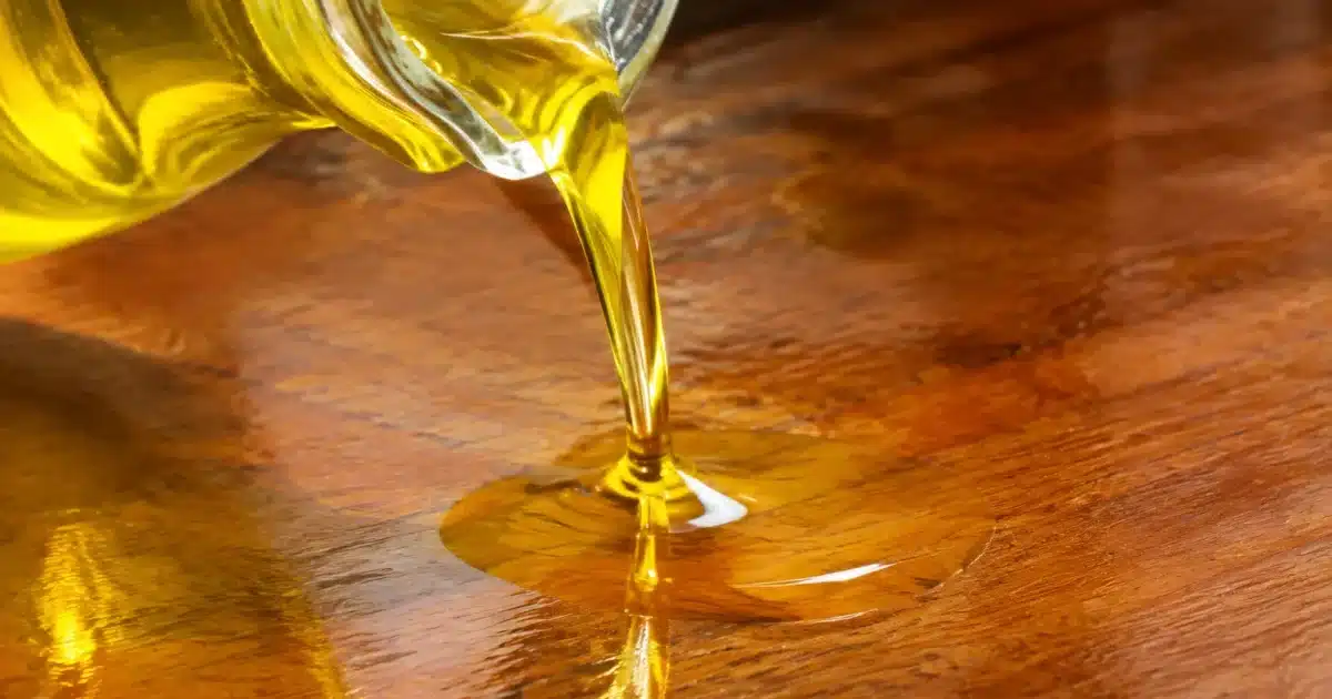 Liquide jaune versé sur surface bois brillante