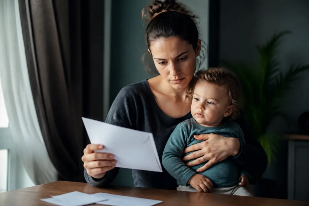 Mere isolee tenant enfant regardant enveloppes blanches