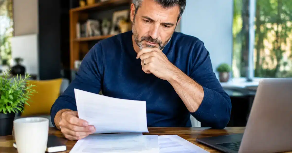 Homme assis consultant documents retraite anticipée sur table