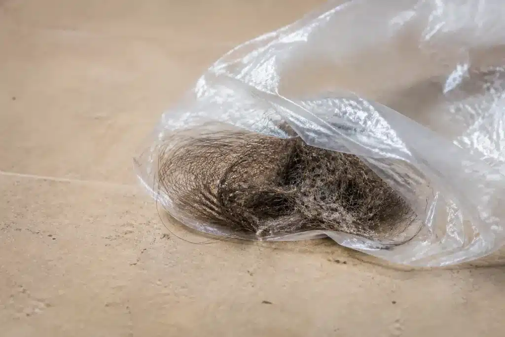 Sac plastique capturant cheveux et poils fins sur sol