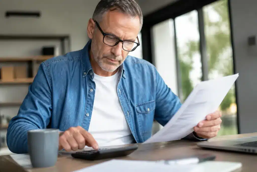 Homme consultant documents financiers retraite avec calculatrice