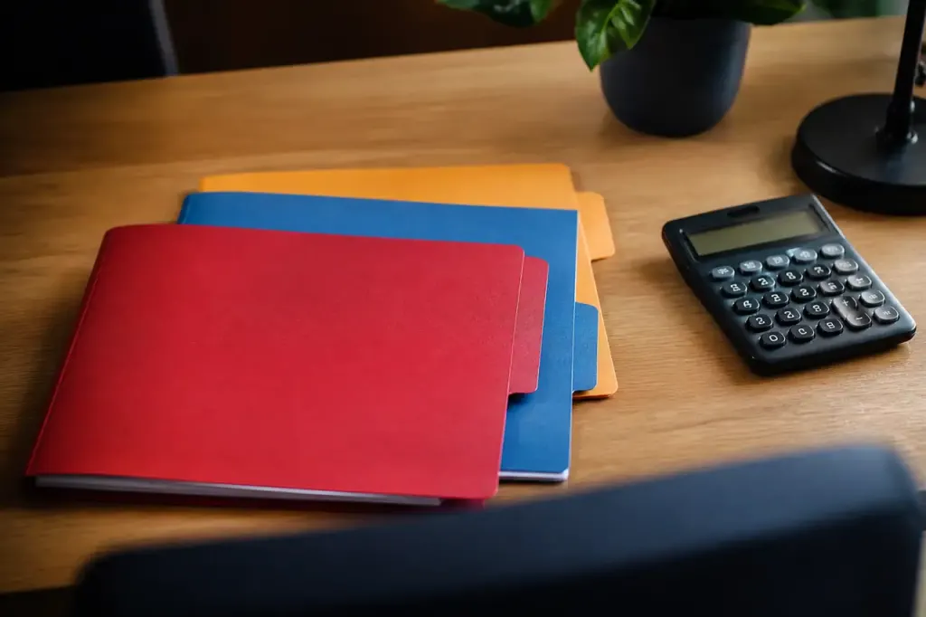 Bureau avec trois dossiers colores et calculatrice