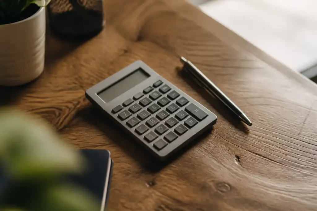 Calculatrice grise et stylo sur table en bois