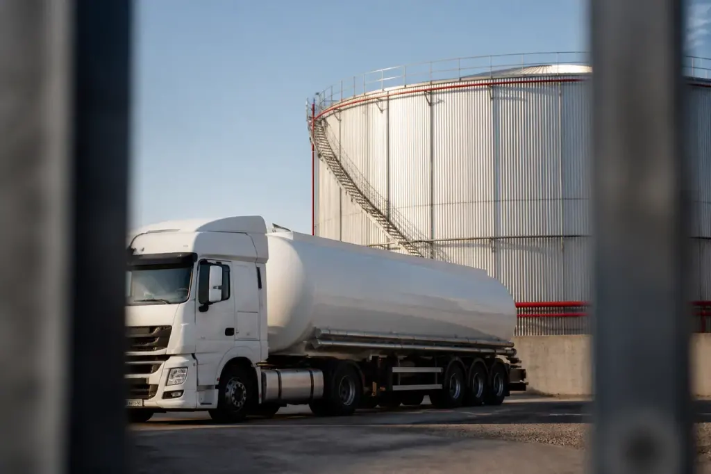 Camion citerne blanc gare devant une cuve metallique