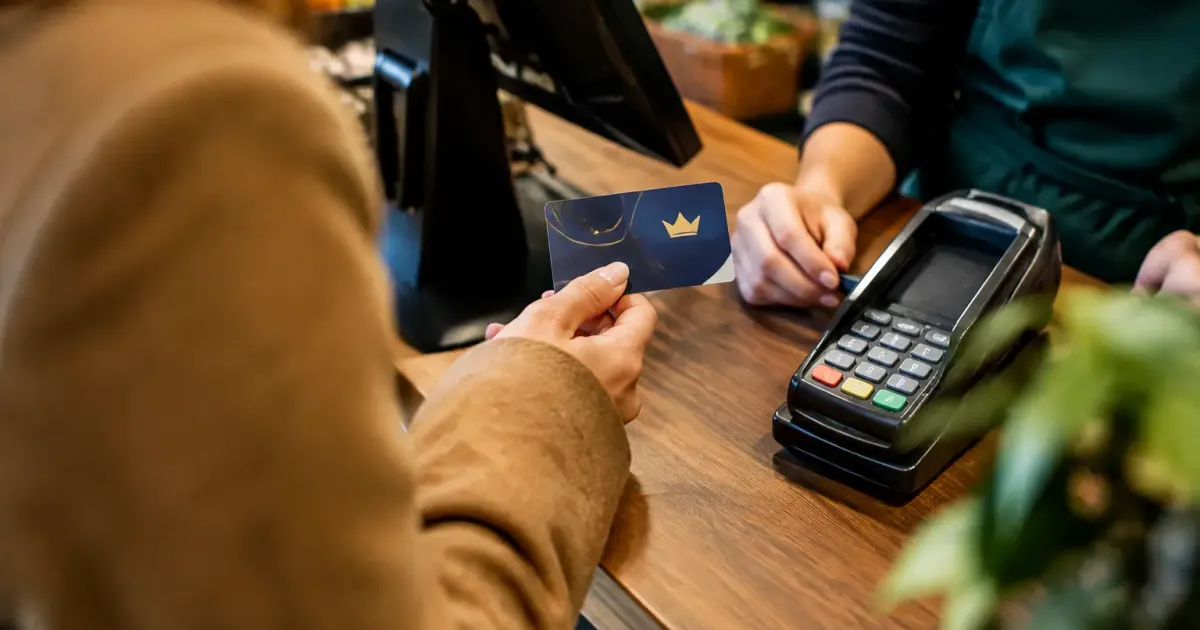 Client tenant une carte de fidelite devant une caisse