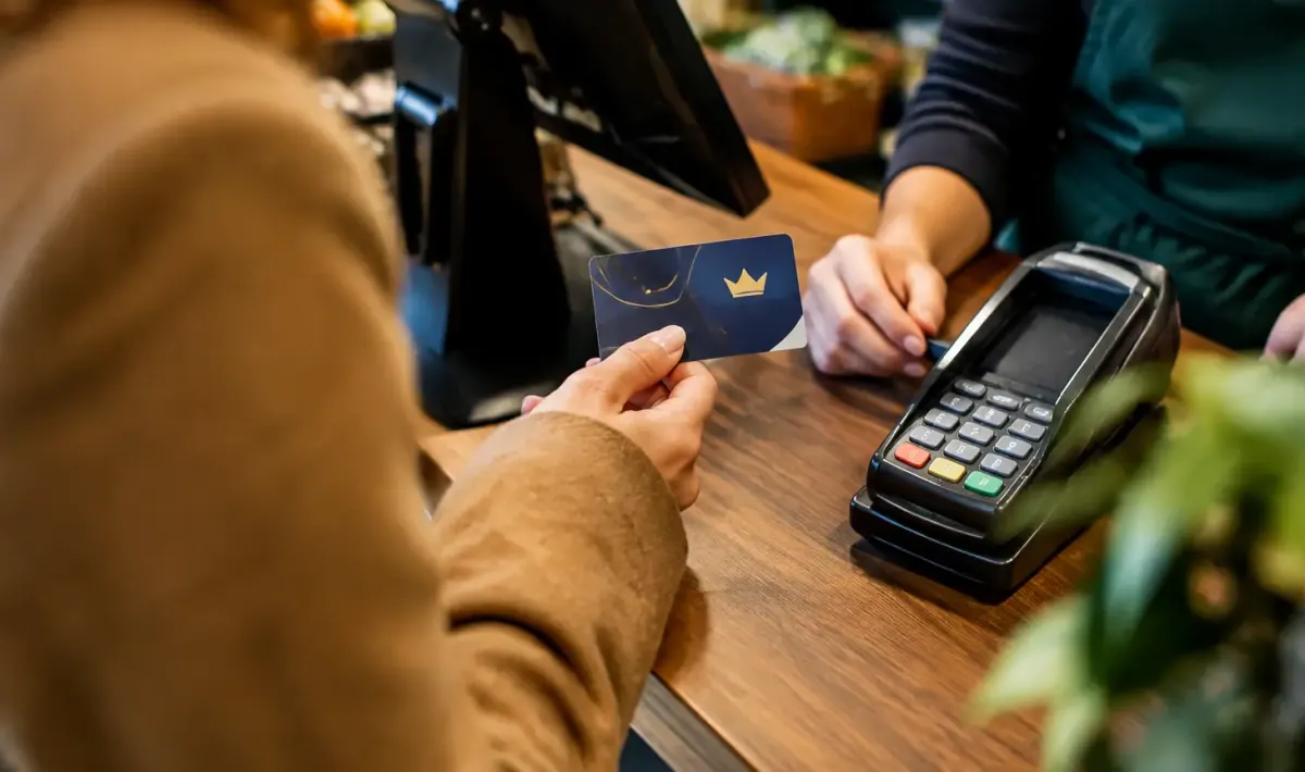 Client tenant une carte de fidelite devant une caisse