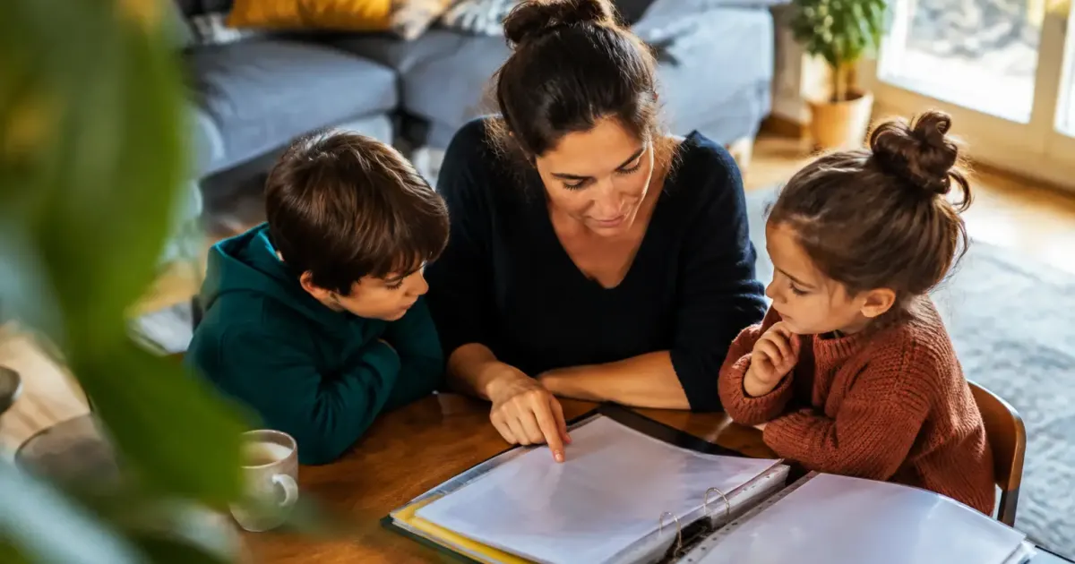 Femme assise avec deux enfants, classeur ouvert sur table
