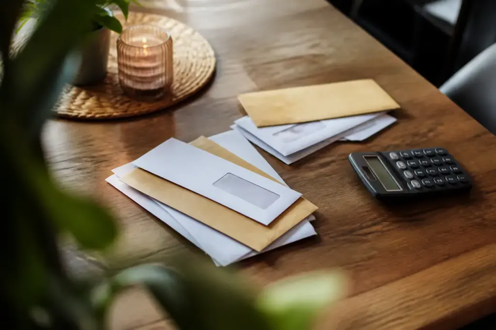 Femme assise devant une table avec enveloppes et calculatrice