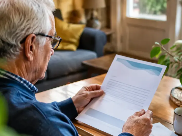 Homme retraite assis lisant un courrier de mutuelle