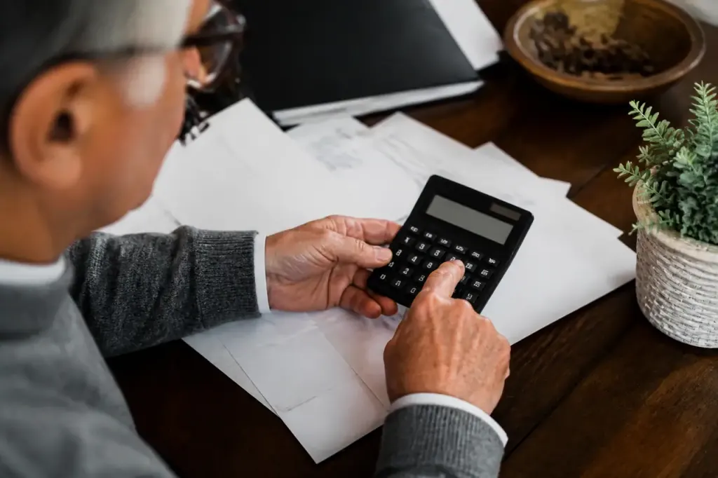 Homme senior pose une calculatrice sur des factures