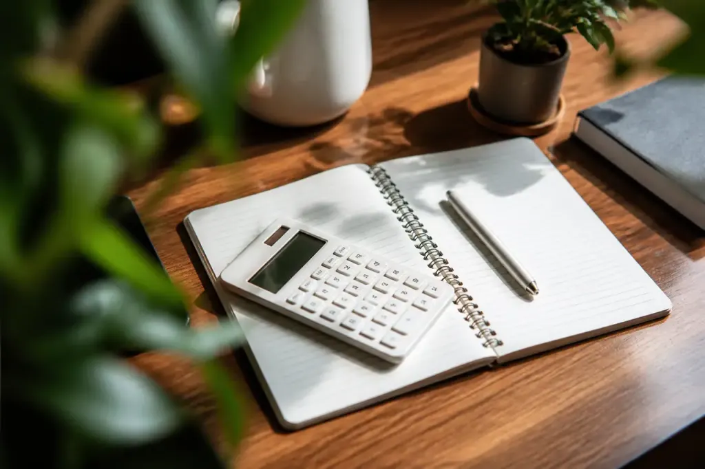 Mains tenant une calculatrice sur un carnet ouvert