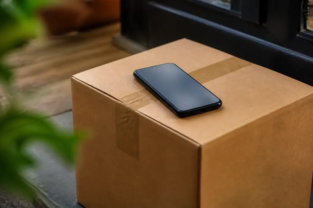 Smartphone affichant un SMS de colis sur carton