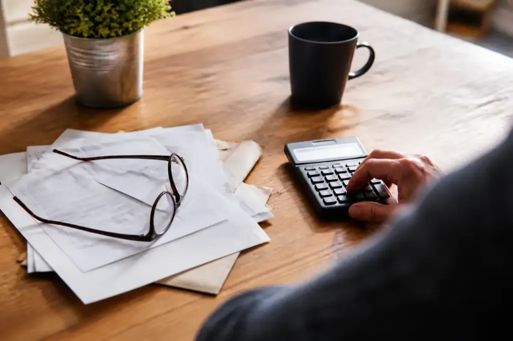 Table en bois avec calculatrice, factures et lunettes