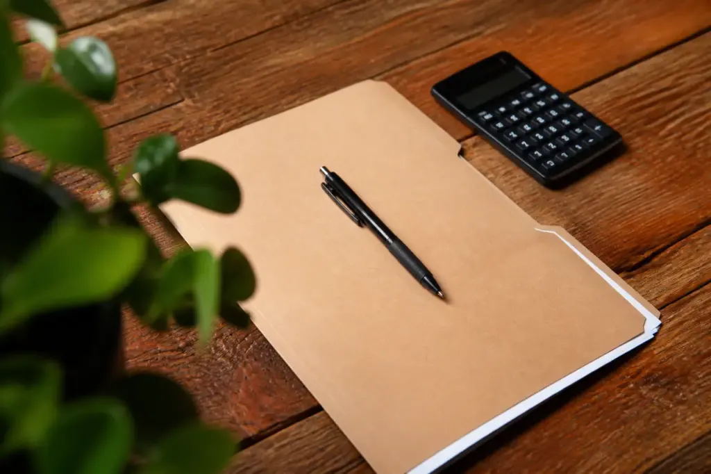 Table en bois avec dossier papier, stylo et calculatrice